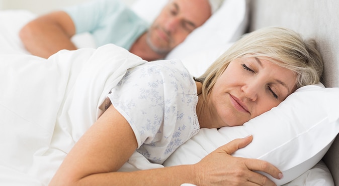 Older woman sleeping in bed with husband, Better Sleep Council